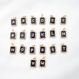 Kinsey Designs Archives' Initial Tile Necklace Ink Letter W features a gold-outlined black pendant with a white "W," displayed alphabetically with other letters on a white surface.