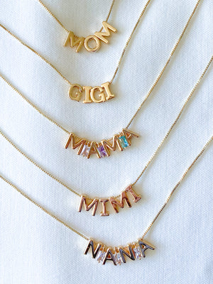 Six adjustable Charm Bar Necklace Box Chain - Kinsey Charm Bar necklaces with pendant letters spelling "MOM," "GIGI," "MAMA," "MIMI," and "NANA" on a white background.