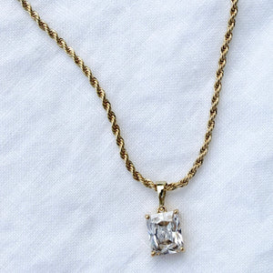 The Martin Necklace by Kinsey Designs Archives features a 19" twisted gold filled chain with a rectangular cubic zirconia pendant, elegantly displayed on a white fabric background.