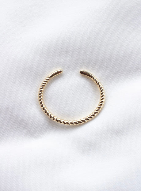 The Fallon Baby Cuff by Kinsey Designs is an adjustable, nickel-free gold-filled twisted open cuff bracelet, elegantly displayed on a white fabric background.