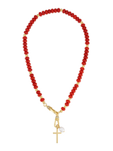 The Katherine Cross Gemstone Necklace by Kinsey Designs features red carnelian beads, gold accents, a cross pendant, and a white pearl charm for a unique statement look.