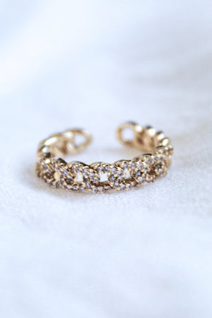 The Ava Lux Ring by Kinsey Designs Archives is a gold-plated, chain-style adjustable ring adorned with sparkling cubic zirconia, shown on a soft white background.