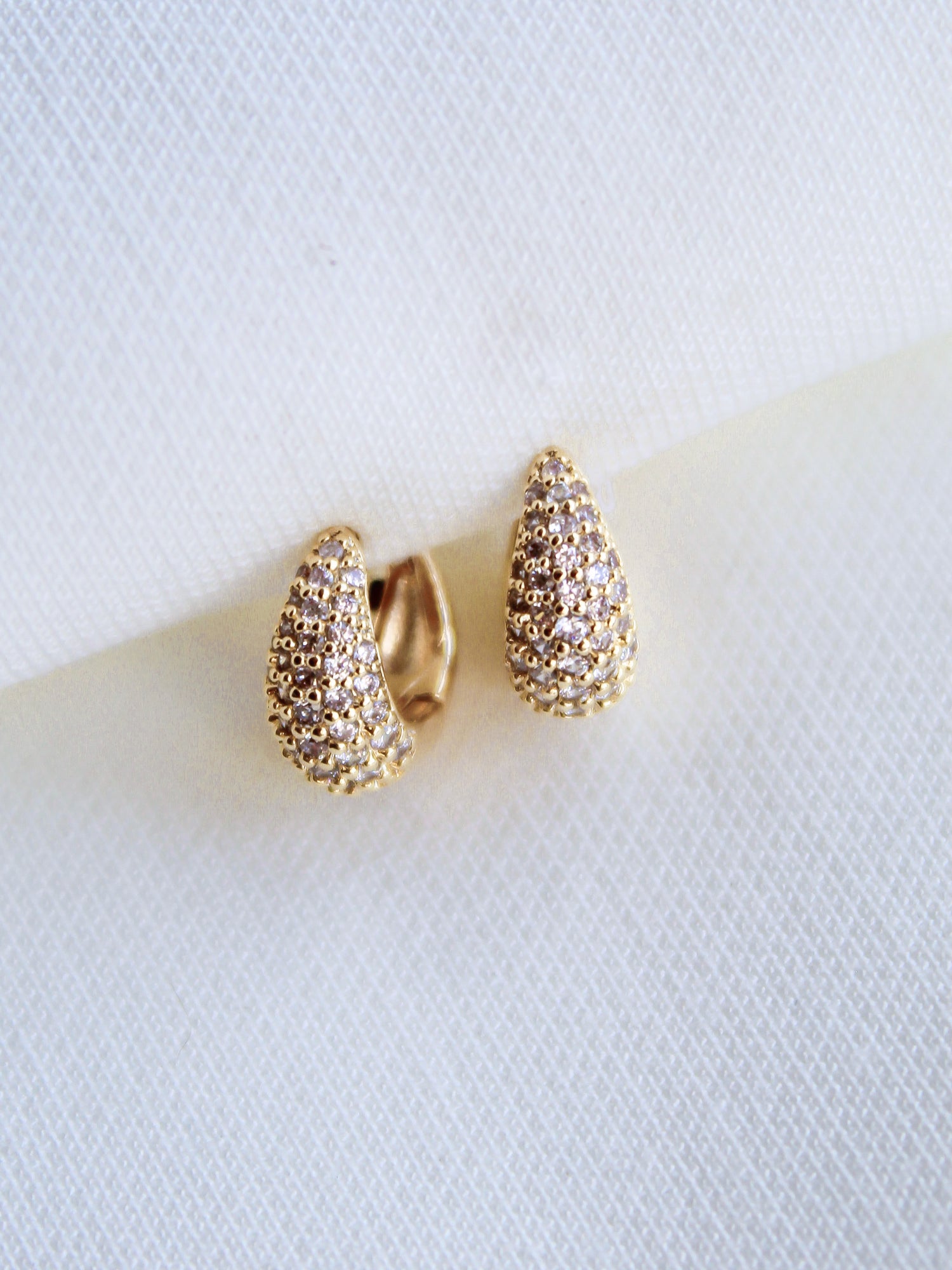 The Beeba Huggie by Kinsey Designs Archives are gold plated earrings with a textured finish, measuring 0.5 inch and displayed on a white fabric background.