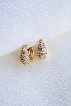 The Beeba Huggie by Kinsey Designs Archives are gold plated earrings with a textured finish, measuring 0.5 inch and displayed on a white fabric background.