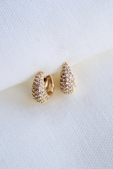 The Beeba Huggie by Kinsey Designs Archives are gold plated earrings with a textured finish, measuring 0.5 inch and displayed on a white fabric background.