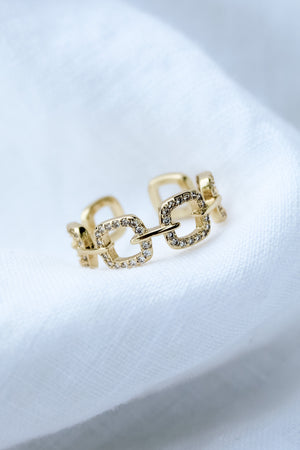 The Billie Ring by Kinsey Designs features gold-filled, square, diamond-studded links and is displayed on soft white fabric.
