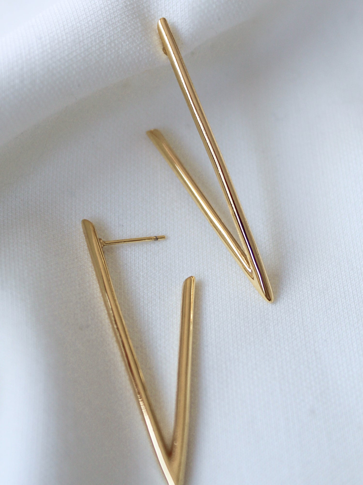 The Bowen Earring by Kinsey Designs features two gold-filled, V-shaped earrings displayed on white fabric—elevate your style with this exclusive sample sale piece.