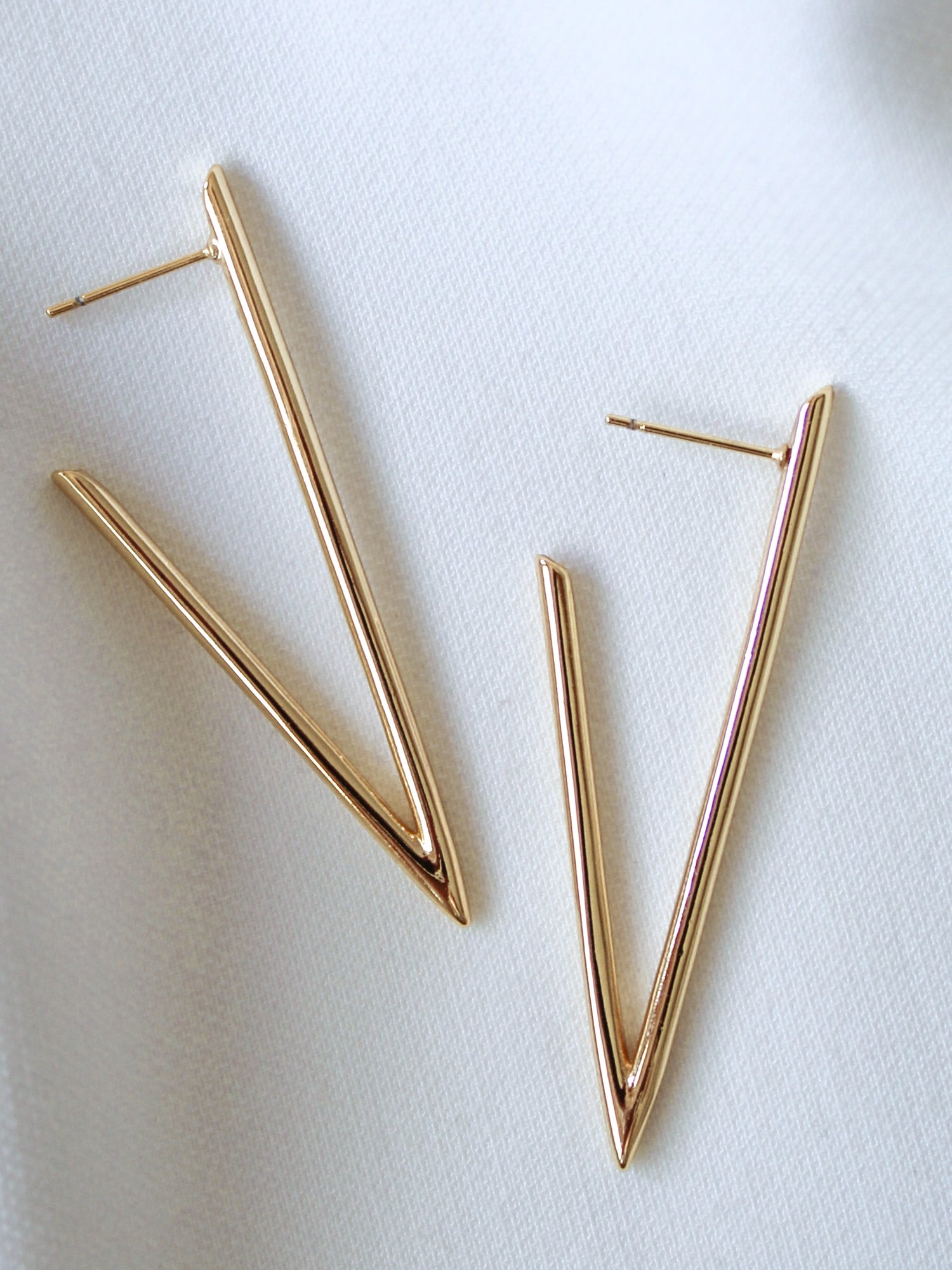 The Bowen Earring by Kinsey Designs features a gold-filled V shape, displayed on white fabric. Elevate your style with these elegant earrings—shop now during our exclusive sample sale!.