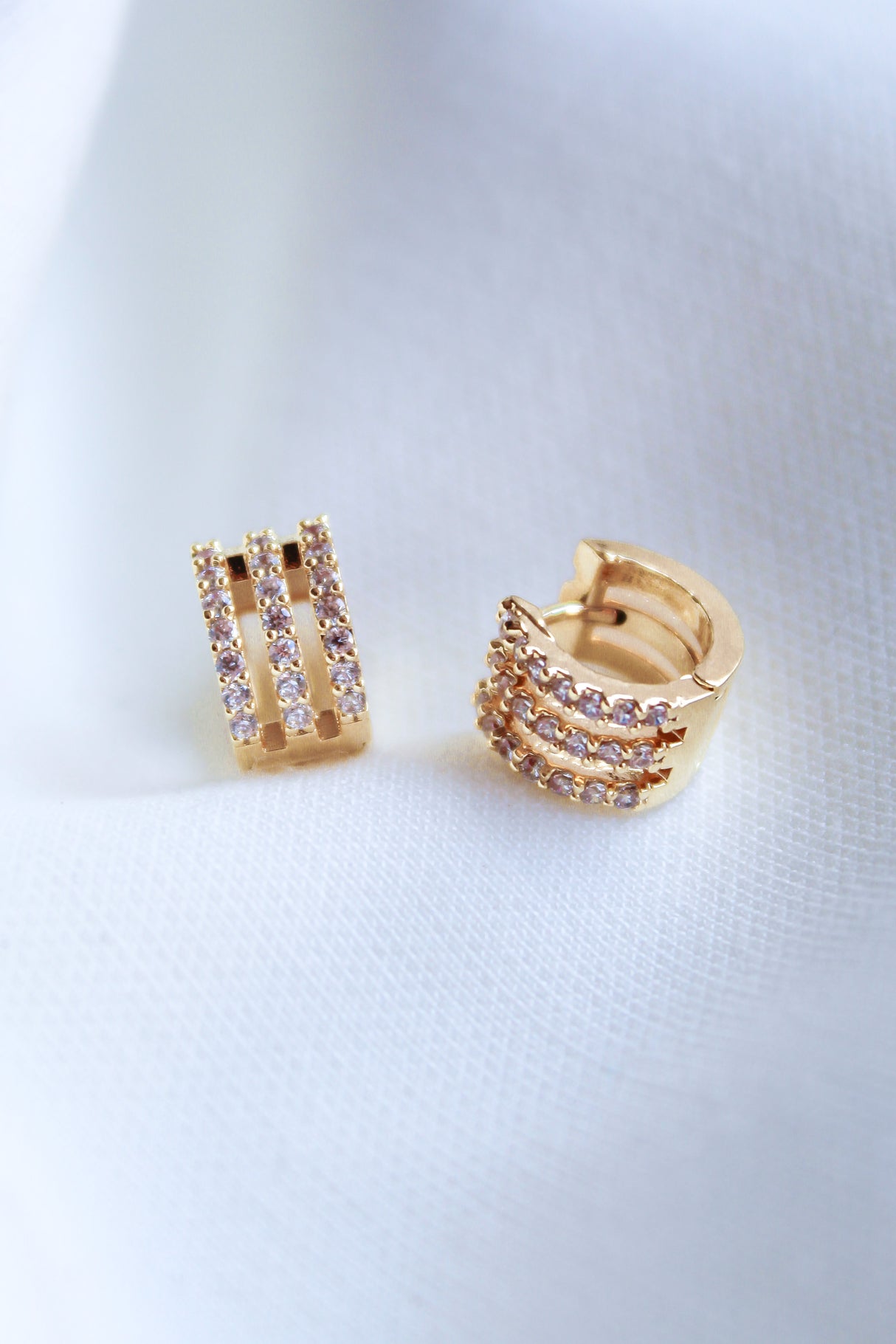 The Bri Huggie by Kinsey Designs Archives features three rows of small, sparkling cubic zirconia stones set on 14k gold plated hoops.
