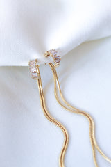 The Callie Earring by Kinsey Designs Archives features 3.5-inch gold-filled earrings with sparkling cubic zirconia drops and long chains, displayed on white textured fabric.