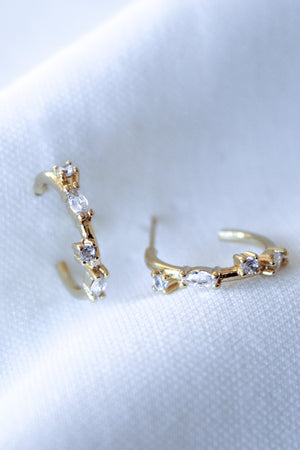 The Chase Hoop Mini earrings by Kinsey Designs are gold filled hoops with a 0.5" diameter and sparkling cubic zirconia, shown on a white textured fabric background.