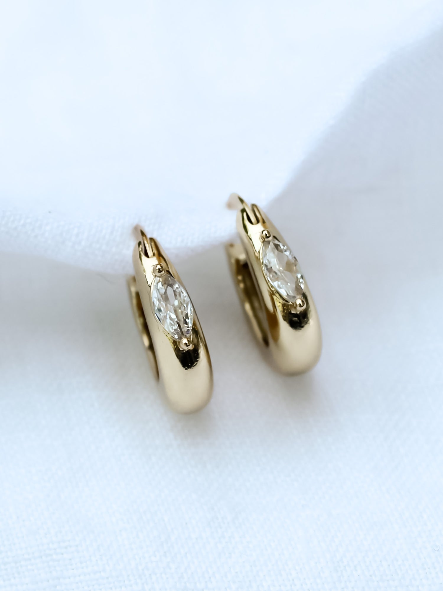 The Claudia Huggie by Kinsey Designs Archives features gold filled hoops with marquise cubic zirconia stones (.75" circumference), shown on a white fabric background.