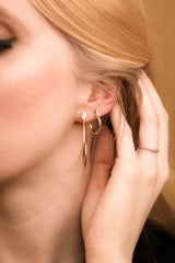 Close-up of a woman’s ear wearing Kinsey Designs Archives' Darra Hoop Large gold-plated earrings, with her hand touching her hair and a gold ring—ideal for elevating your sample sale chic look.