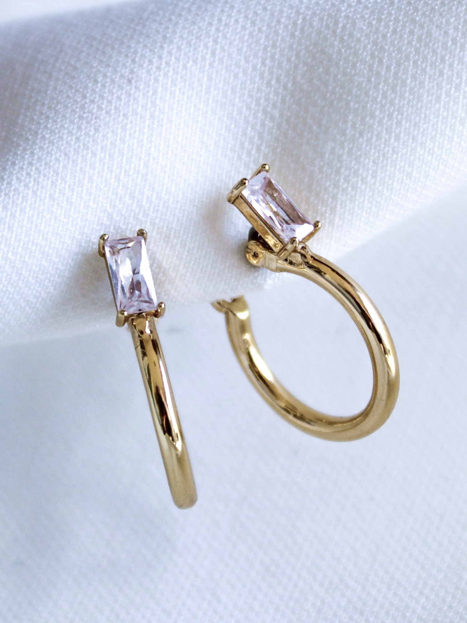 The Darra Hoop Mini by Kinsey Designs Archives are gold plated hoop earrings with a .75" diameter, adorned with rectangular clear cubic zirconia gemstones, displayed on a white fabric background.