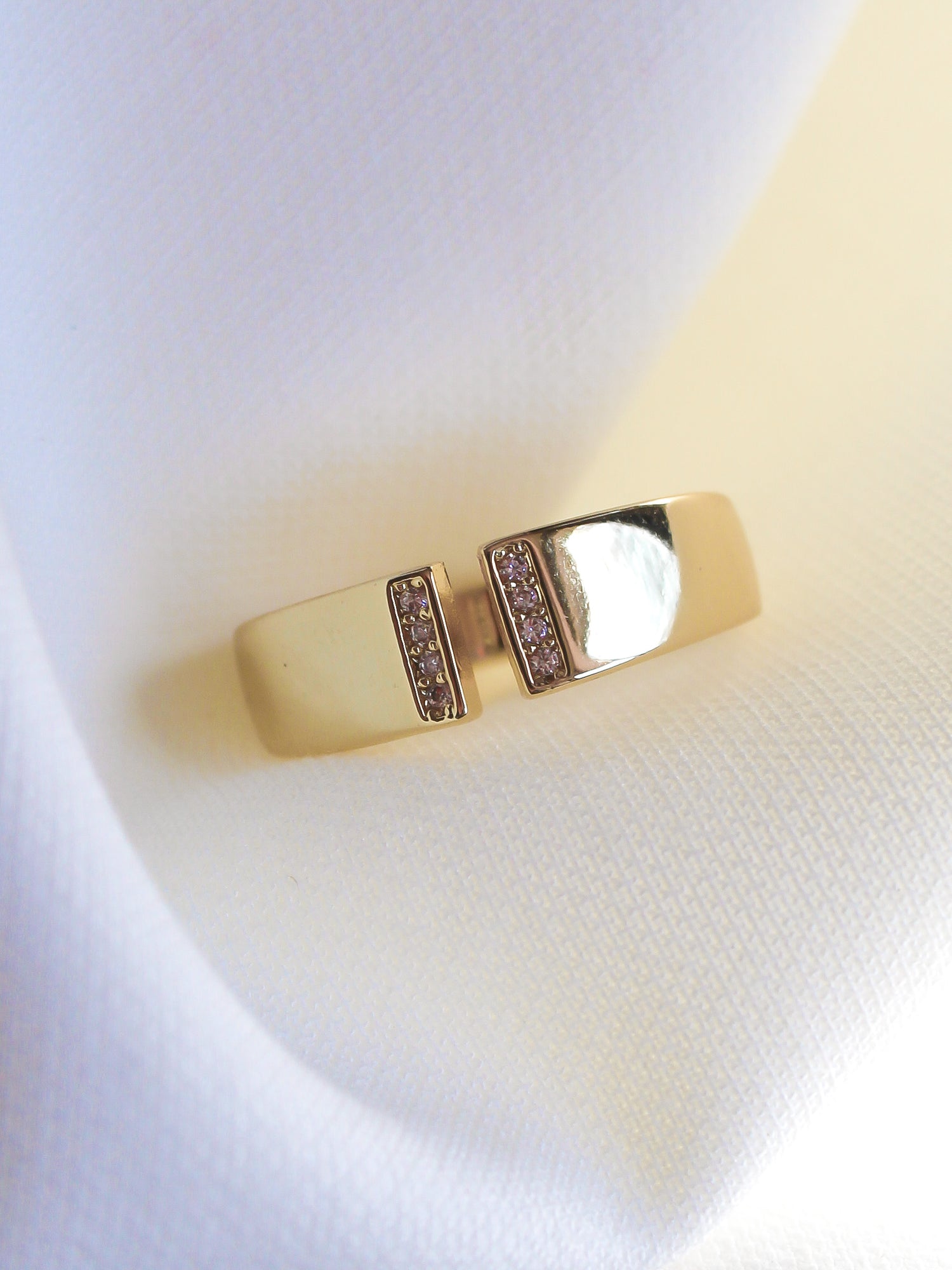 The Dean Ring by Kinsey Designs Archives features two parallel bars with sparkling cubic zirconia on a gold-plated band, shown on white textured fabric. Size 6.