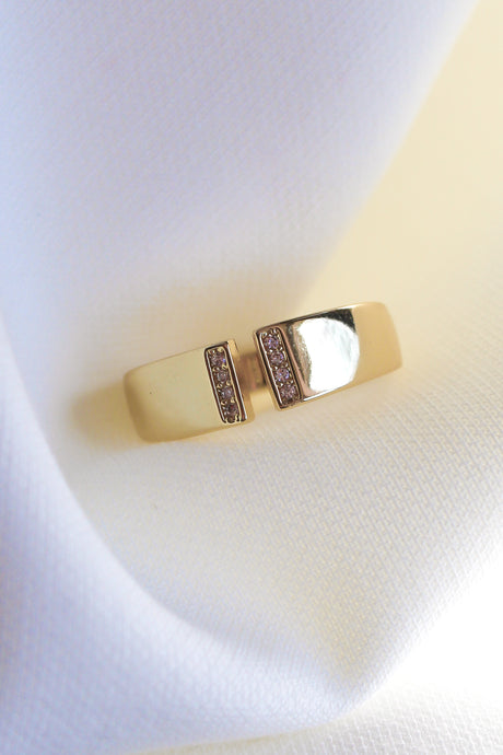 The Dean Ring by Kinsey Designs Archives features two parallel bars with sparkling cubic zirconia on a gold-plated band, shown on white textured fabric. Size 6.