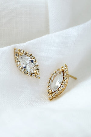 The Dina Post by Kinsey Designs Archives features gold filled marquise-shaped stud earrings with cubic zirconia and a halo of small diamonds, beautifully displayed on white fabric.