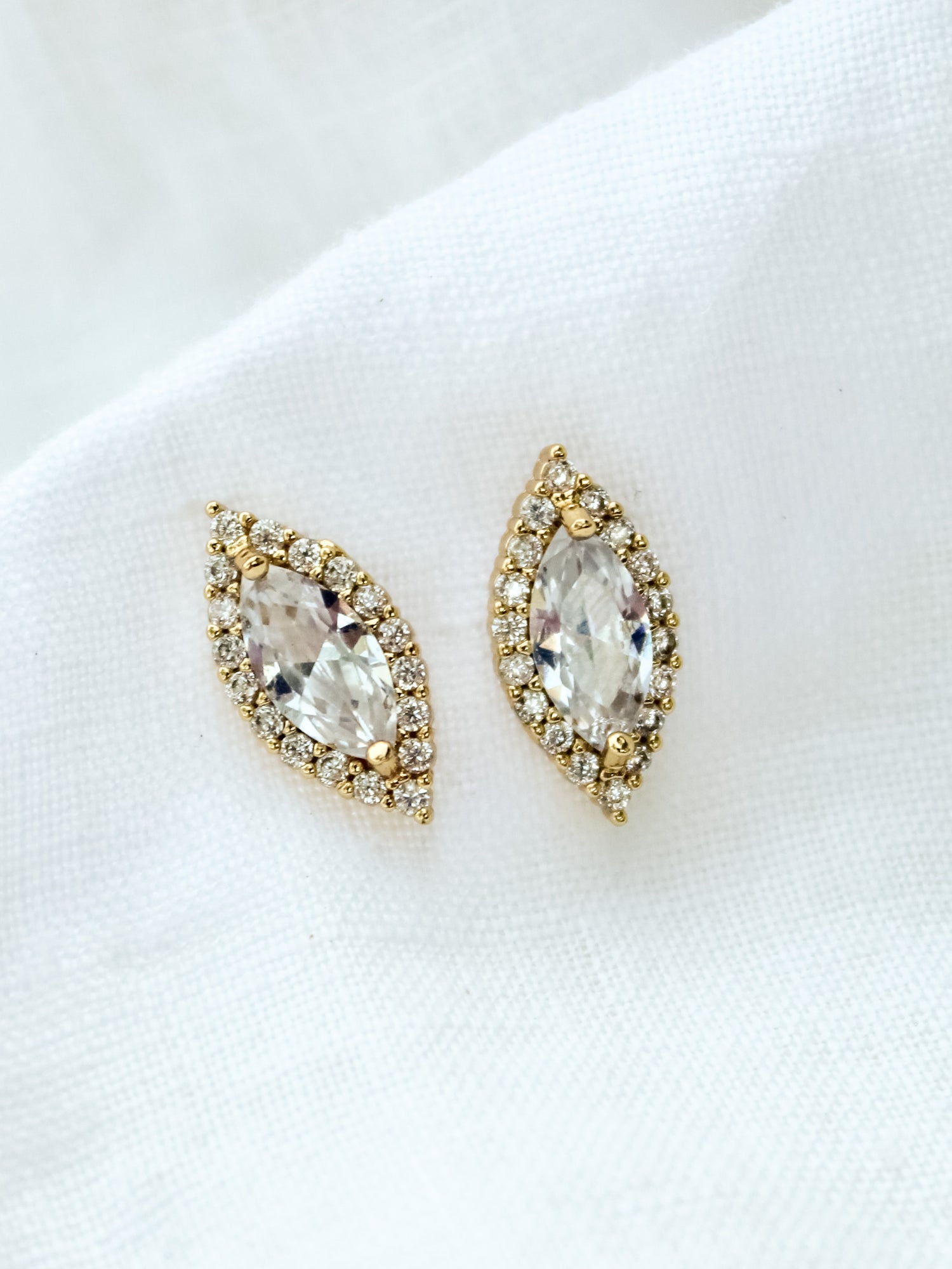 The Dina Post marquise-shaped stud earrings by Kinsey Designs Archives are shown on a white fabric background.