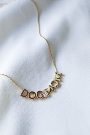 Dog Mom Slide Necklace by Kinsey Designs Archives shown on white fabric, featuring “DOG MOM” gold letter charms on an 18" gold filled chain with adjustable Italian closure.