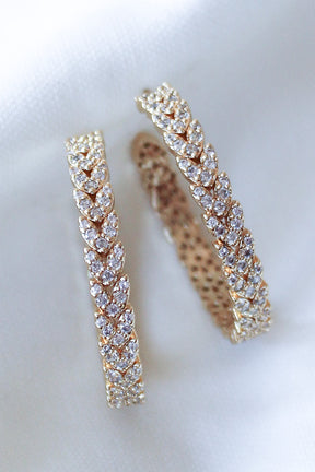 The Dottie Heart Hoop by Kinsey Designs Archives features a leaf pattern with sparkling cubic zirconia, showcased on a white fabric background.