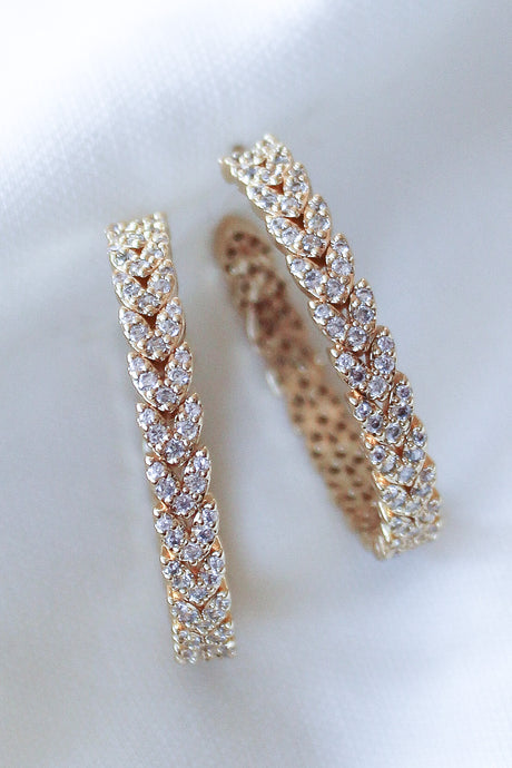 The Dottie Heart Hoop by Kinsey Designs Archives features a leaf pattern with sparkling cubic zirconia, showcased on a white fabric background.