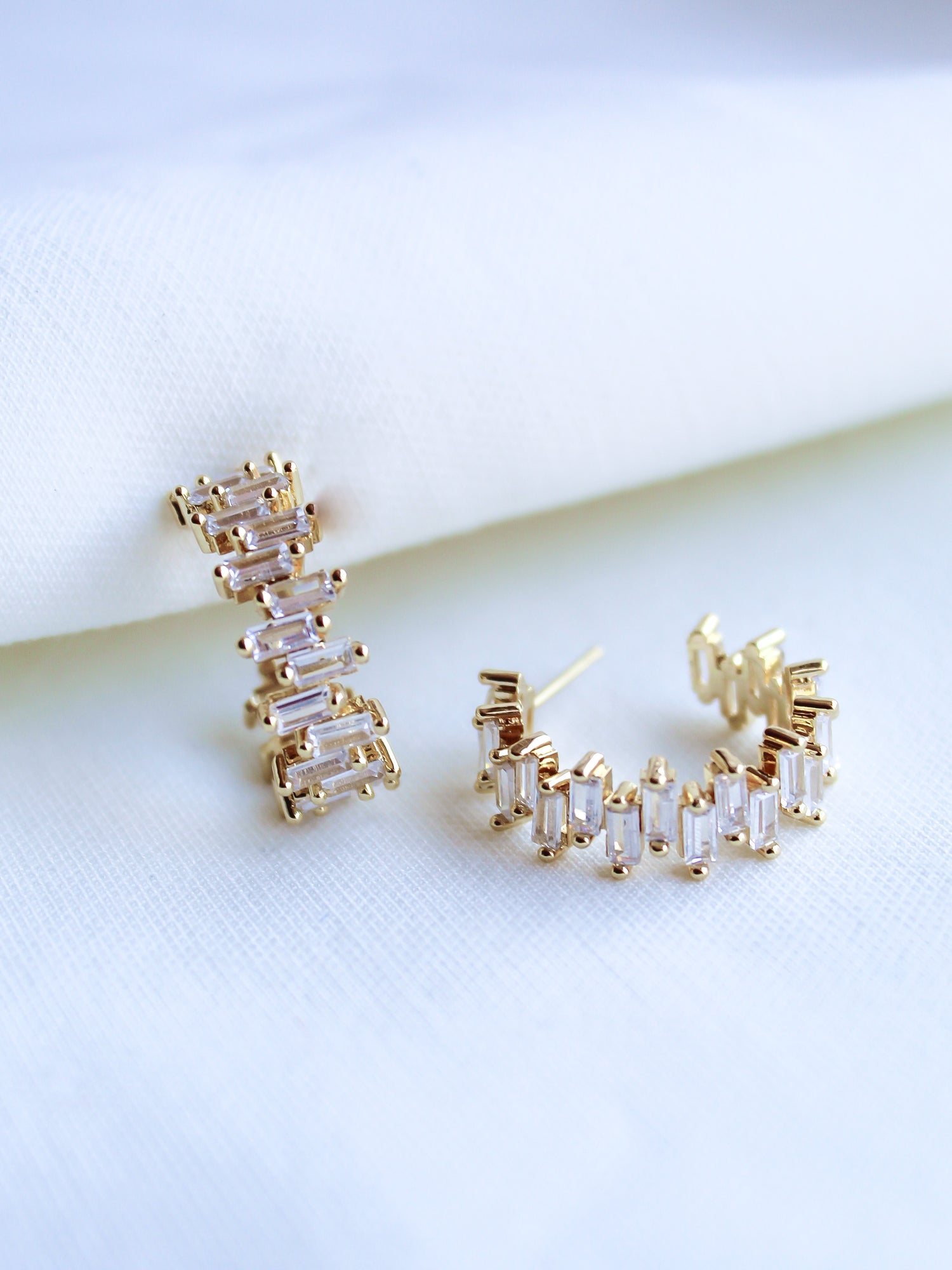The Ettie Hoop by Kinsey Designs Archives is a pair of gold filled earrings with 1" diameter, featuring rectangular cubic zirconia stones in a row, shown on a white fabric background.