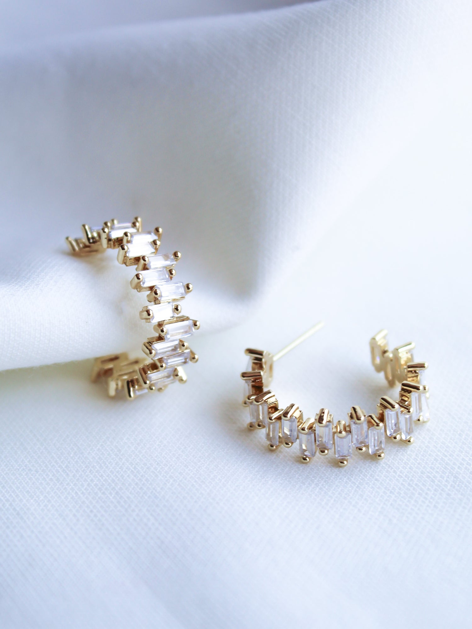 The Ettie Hoop by Kinsey Designs Archives features 1" gold-filled hoops adorned with rectangular cubic zirconia, elegantly displayed on white fabric.