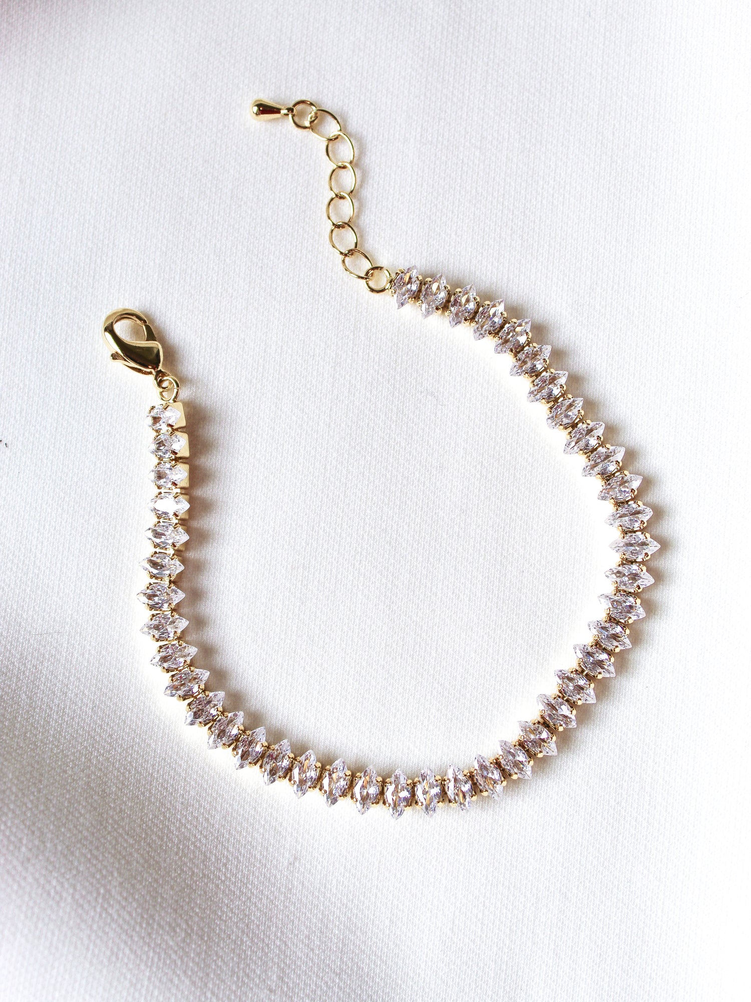 The Gator Bracelet by Kinsey Designs Archives features a gold filled 6.5-inch chain with sparkling gemstones and an extender, displayed on a white fabric background.