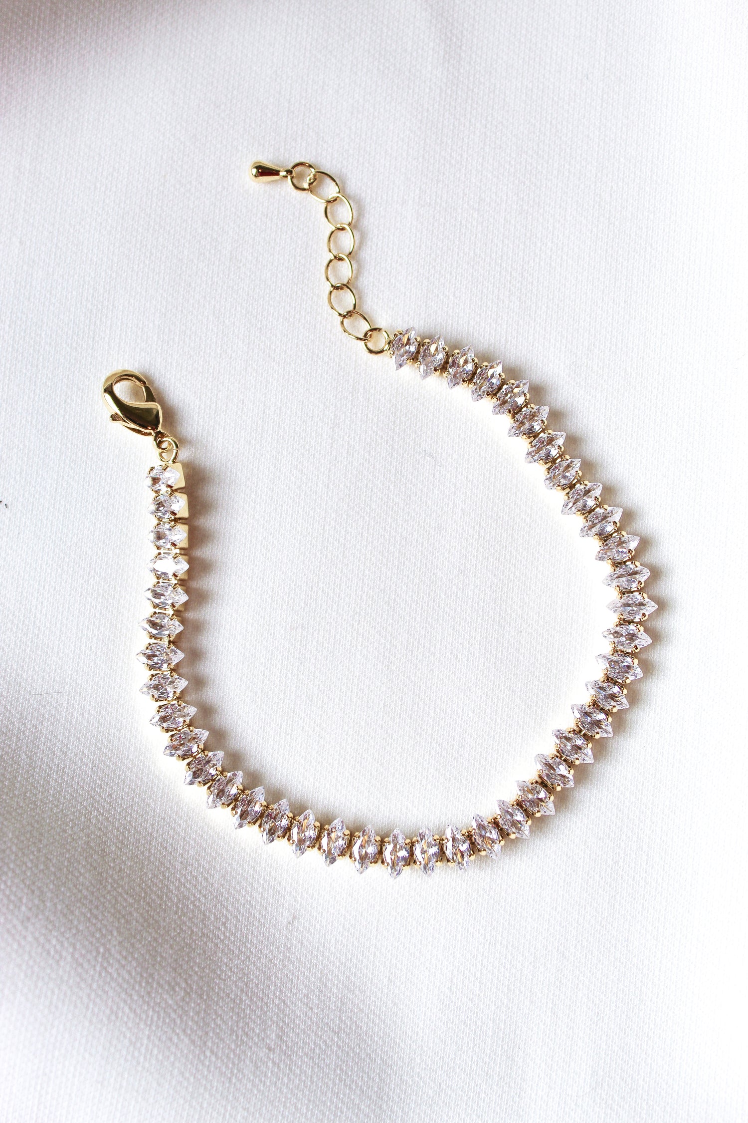 The Gator Bracelet by Kinsey Designs Archives features a gold filled 6.5-inch chain with sparkling gemstones and an extender, displayed on a white fabric background.