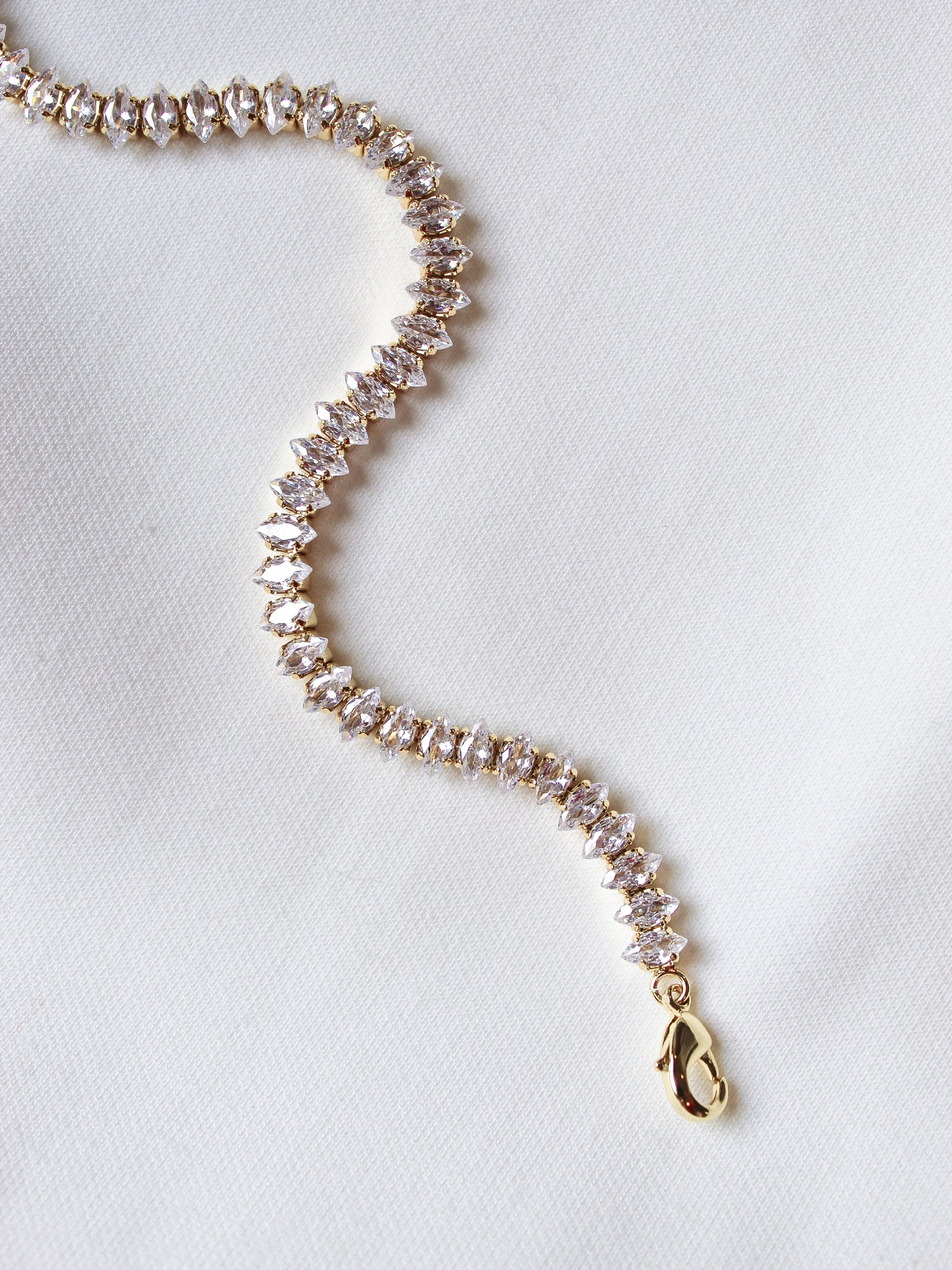 The Gator Bracelet by Kinsey Designs Archives features a gold filled chain with sparkling stones, a 6.5-inch length, and an extender for a perfect fit, shown on a white fabric background.