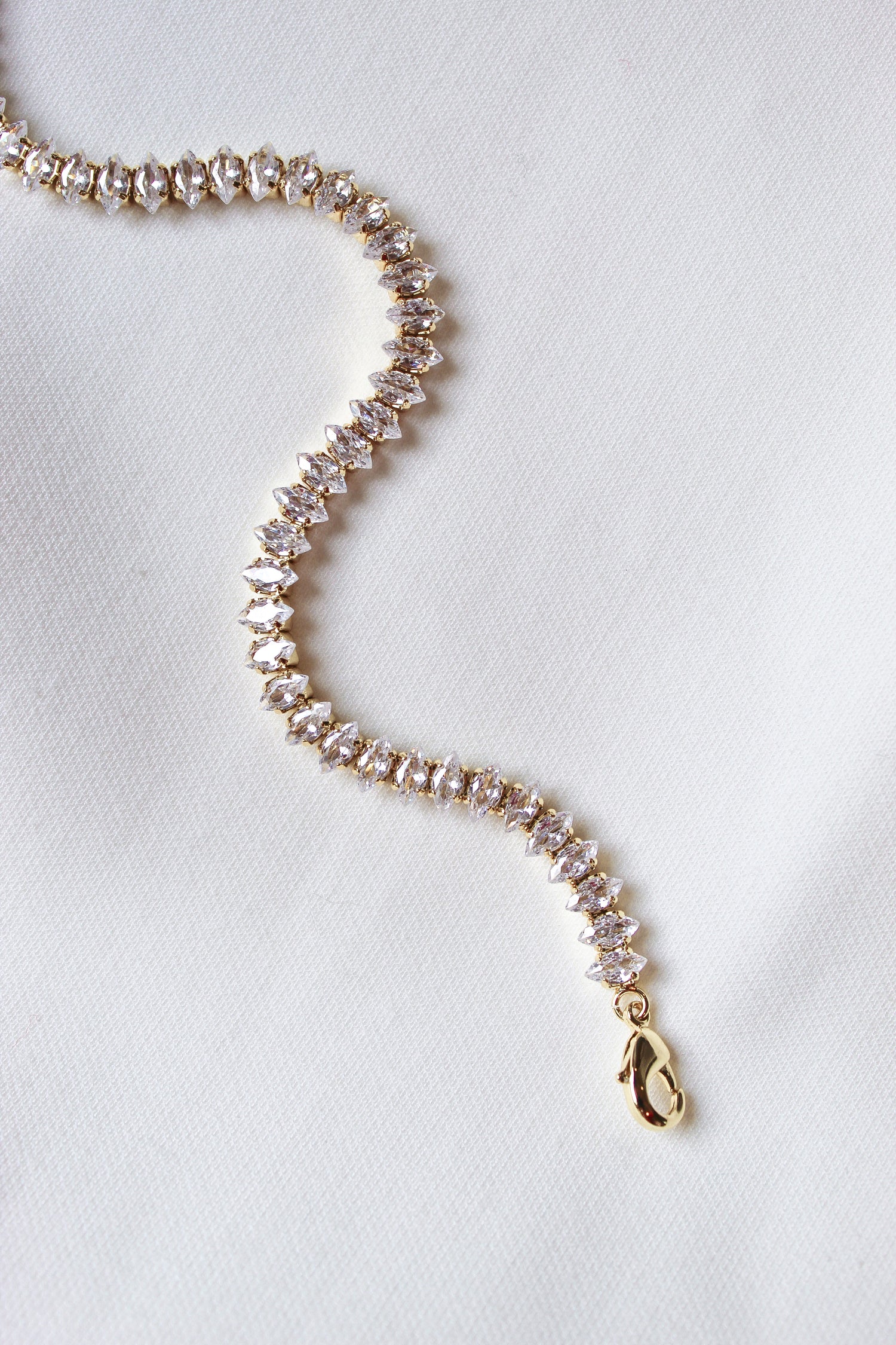 The Gator Bracelet by Kinsey Designs Archives features a gold filled chain with sparkling stones, a 6.5-inch length, and an extender for a perfect fit, shown on a white fabric background.