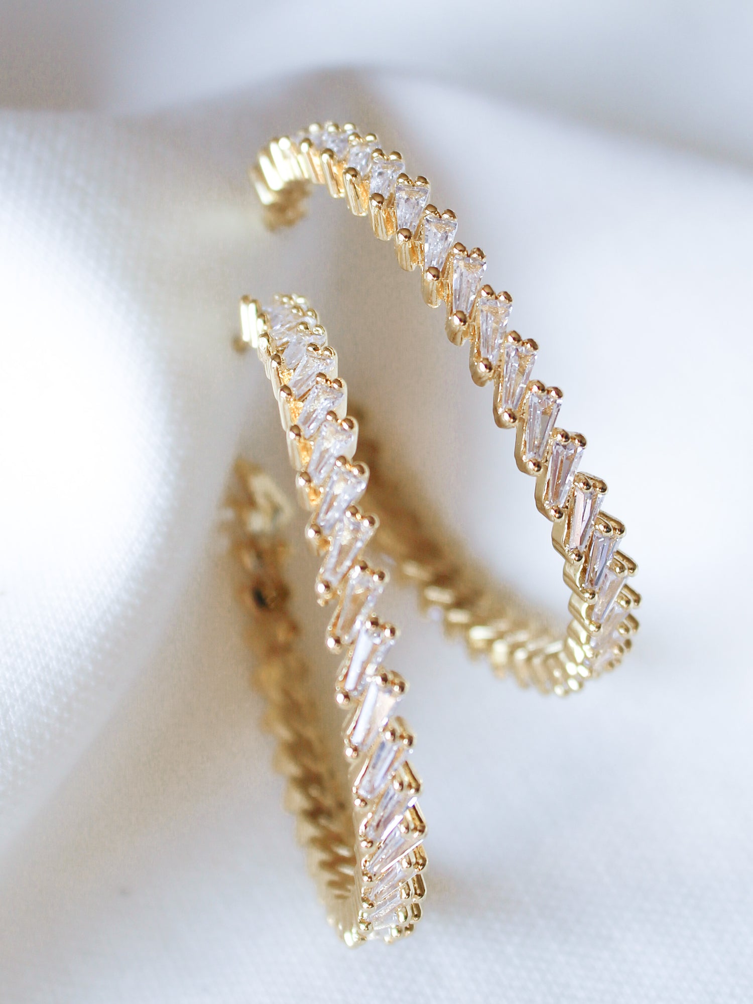 The Graze Hoop by Kinsey Designs Archives features zigzag-set cubic zirconia in gold fill, shown on white fabric. Add sparkle to any look—shop now at our sample sale!.