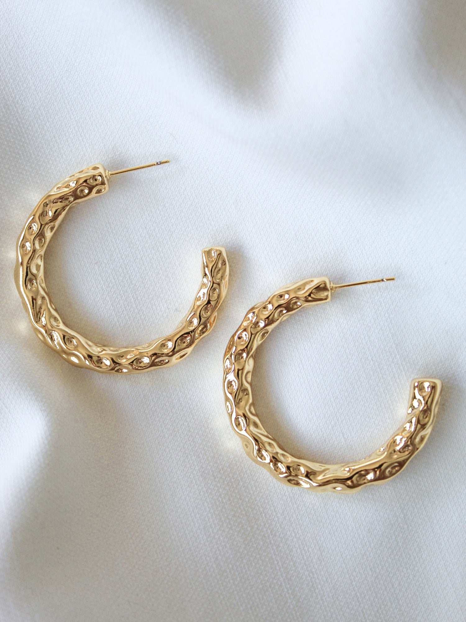 The Hammer Hoop by Kinsey Designs Archives features gold filled textured hoops, 1.5" in diameter, displayed on a white fabric background.