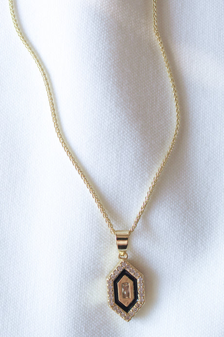The Harlowe Necklace by Kinsey Designs Archives features a gold filled chain (17.75 in) with a hexagon cubic zirconia pendant accented with diamonds, displayed on textured white fabric for an elegant look.