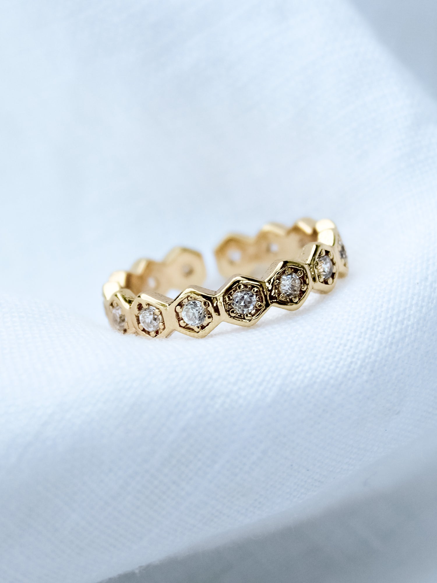 The Heba Ring by Kinsey Designs Archives features 18k gold-filled hexagonal settings with embedded diamonds. Displayed on soft white fabric, this adjustable piece brings elegance to any gold jewelry collection.