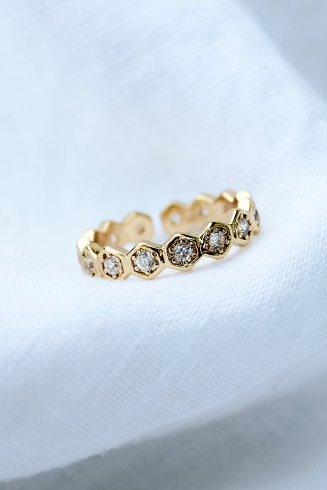 The Heba Ring by Kinsey Designs Archives features 18k gold-filled hexagonal settings with embedded diamonds. Displayed on soft white fabric, this adjustable piece brings elegance to any gold jewelry collection.