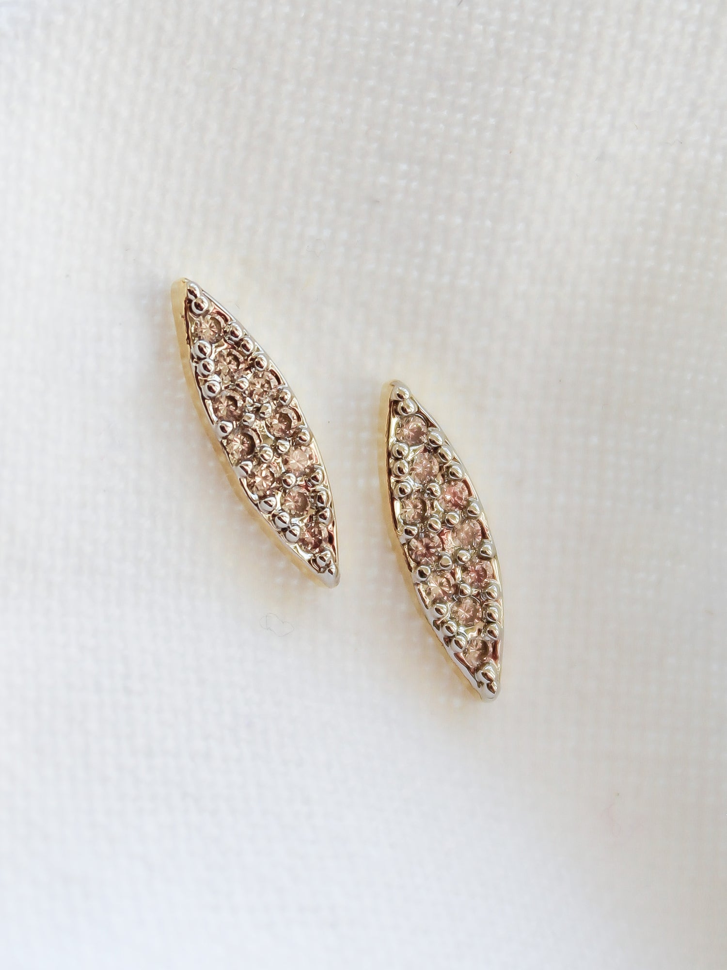 Her Post earrings by Kinsey Designs Archives feature a marquise shape, 0.5" wide, crafted in 16k gold filled metal with sparkling cubic zirconia accents. Shown on a white textured fabric background.