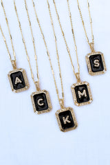 Five gold necklaces from Kinsey Designs Archives, each with a black pendant and a different silver letter—A, G, K, M, S—like the Initial Tile Necklace Ink Letter V.