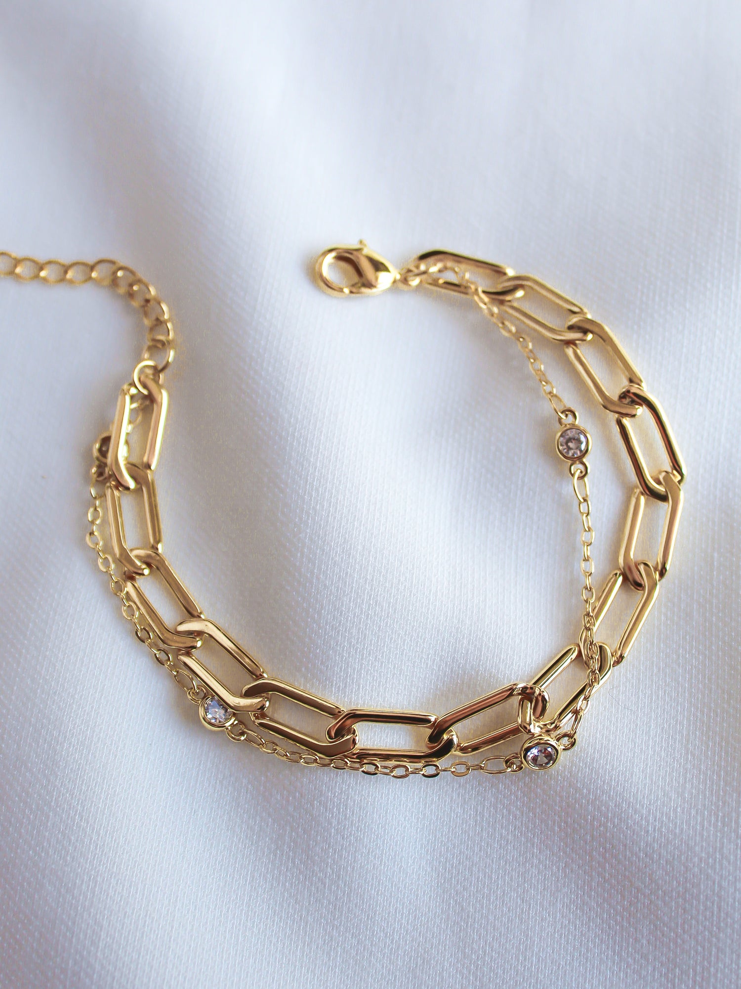 The Lisbon Bracelet by Kinsey Designs Archives features gold-filled rectangular links with small round gemstones. This elegant 6.5" chain is displayed on white fabric—a timeless addition to your gold jewelry collection.