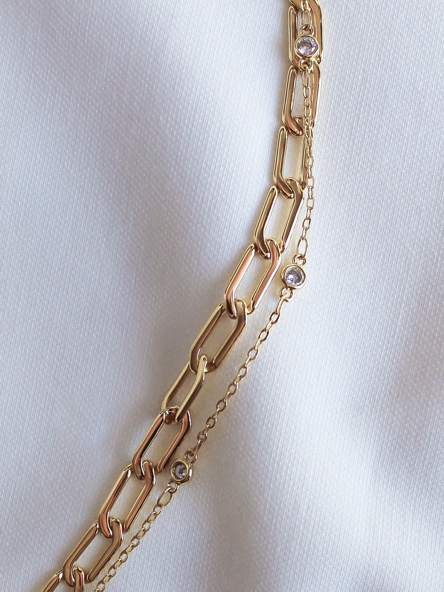 The Lisbon Bracelet by Kinsey Designs Archives rests elegantly on a white fabric background, showcasing its delicate design and sparkling details.