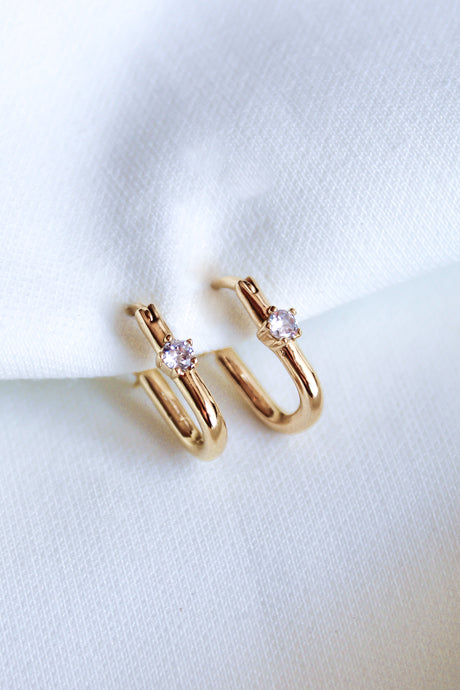The Lou Hoop by Kinsey Designs Archives features 14k gold plating and small clear cubic zirconia gemstones, elegantly displayed on white fabric.