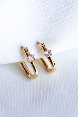 The Lou Hoop by Kinsey Designs Archives features 14k gold plating and small clear cubic zirconia stones, elegantly presented on white fabric.