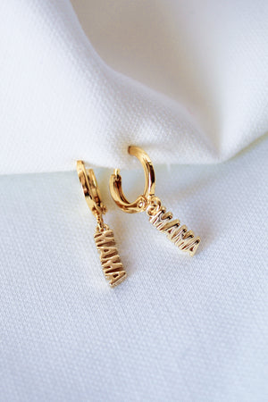 The MAMA Huggies by Kinsey Designs Archives are 1-inch gold filled earrings featuring "MAMA" letter charms, elegantly displayed on white fabric.