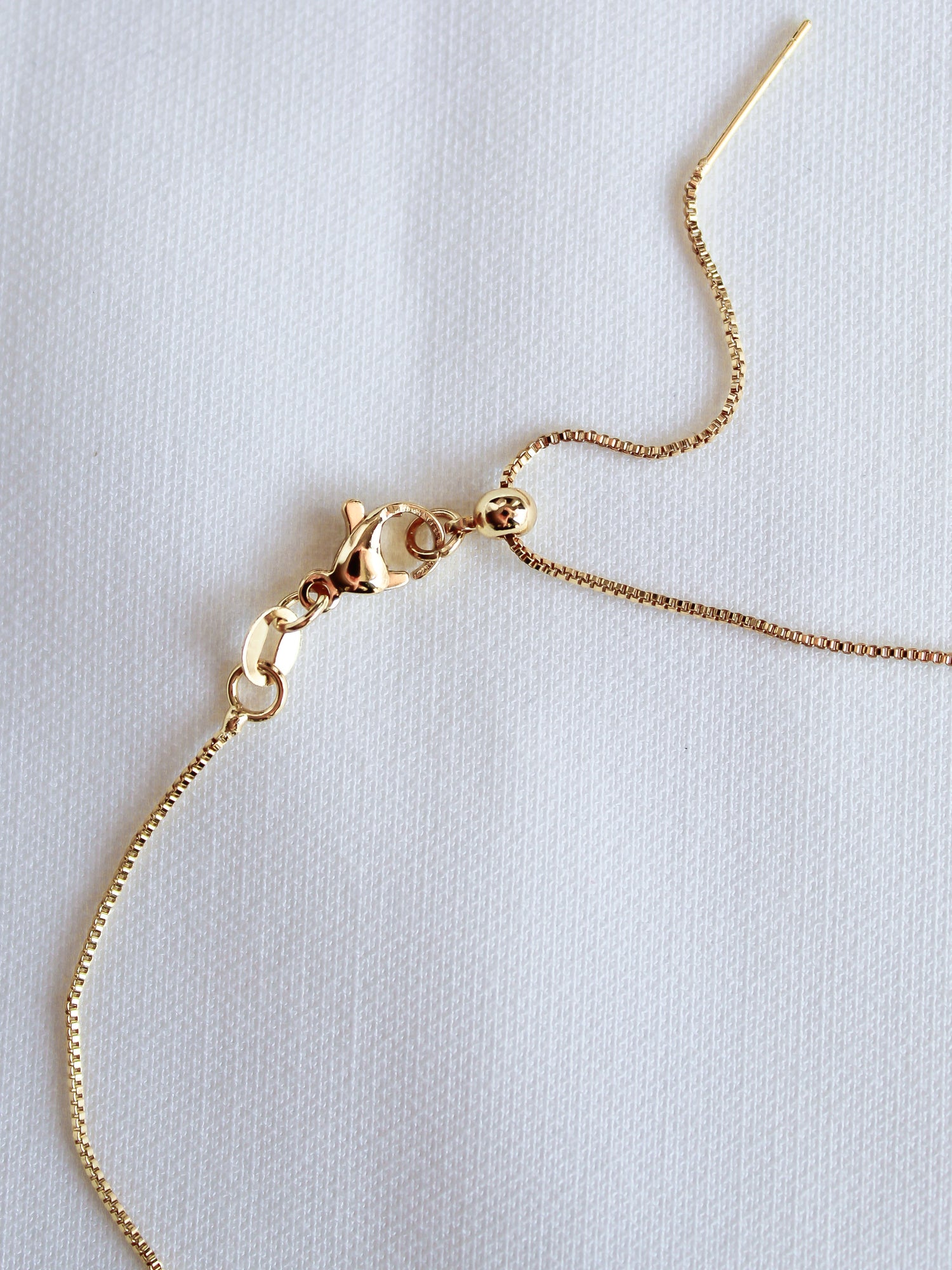 The Dog Mom Slide Necklace by Kinsey Designs Archives, a classic gold filled chain with an adjustable Italian closure and lobster clasp, lies on white textured fabric.