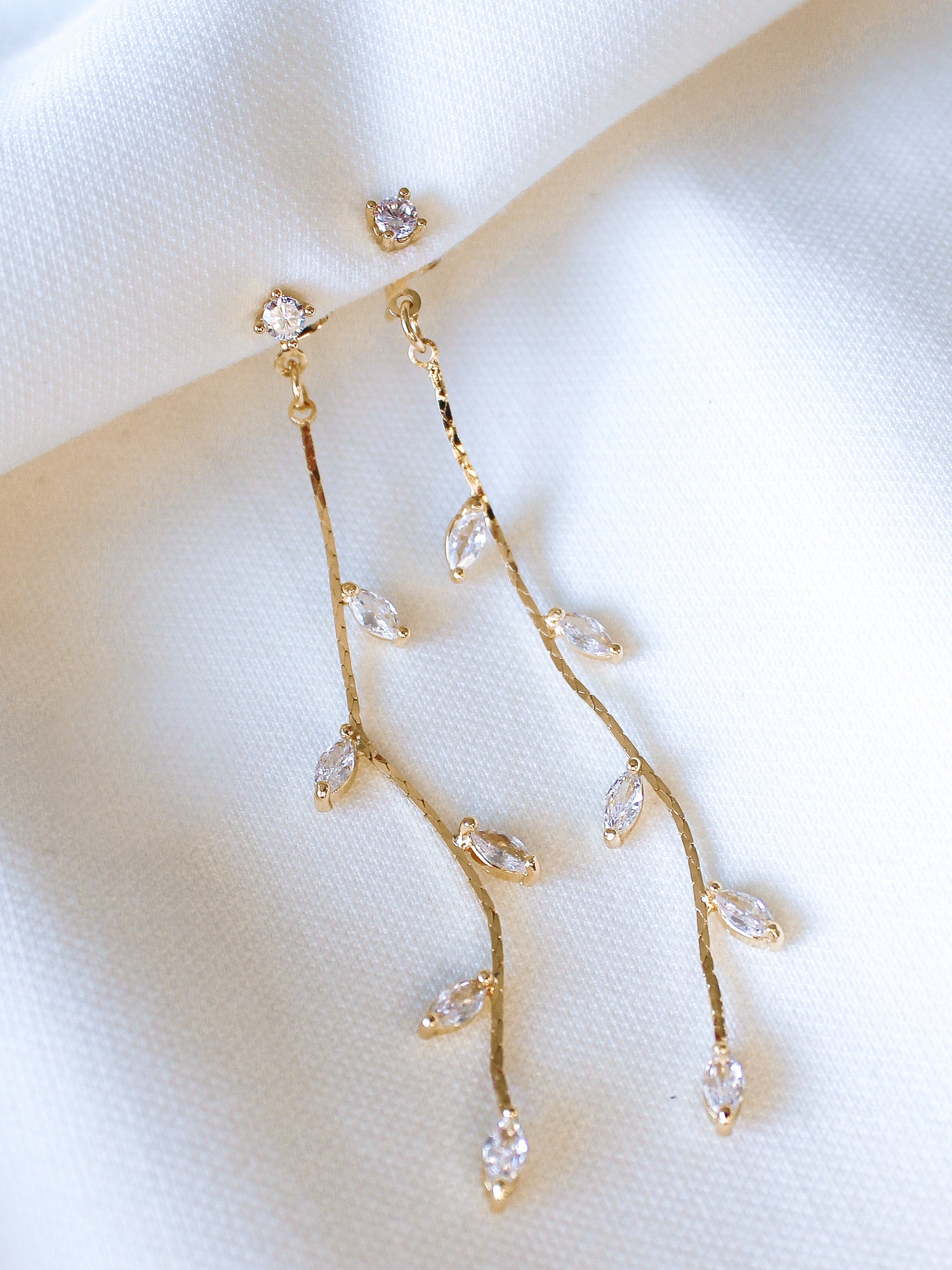 The Parker Earring by Kinsey Designs Archives features gold-filled, branch-style design with cubic zirconia leaves, shown on white fabric—an elegant addition to your style. Shop now at our exclusive sample sale!.