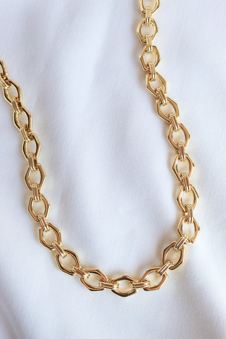 The Prague Necklace by Kinsey Designs Archives features 14k gold filled hexagonal links on an 18" chain, shown on a white fabric background—a modern, elegant accessory for any outfit.