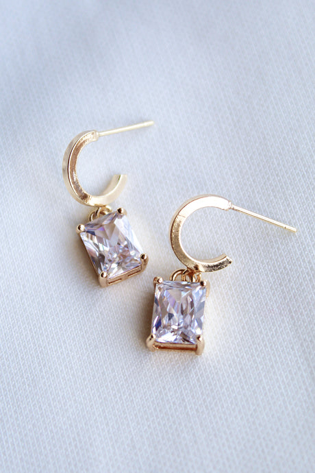 Kinsey Designs Prism Huggies featuring rectangular, princess-cut CZ gemstones, shown on a white fabric background.