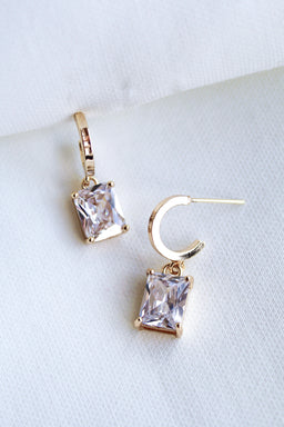 Kinsey Designs Prism Huggies with princess-cut CZ gemstones are shown on a white fabric background.