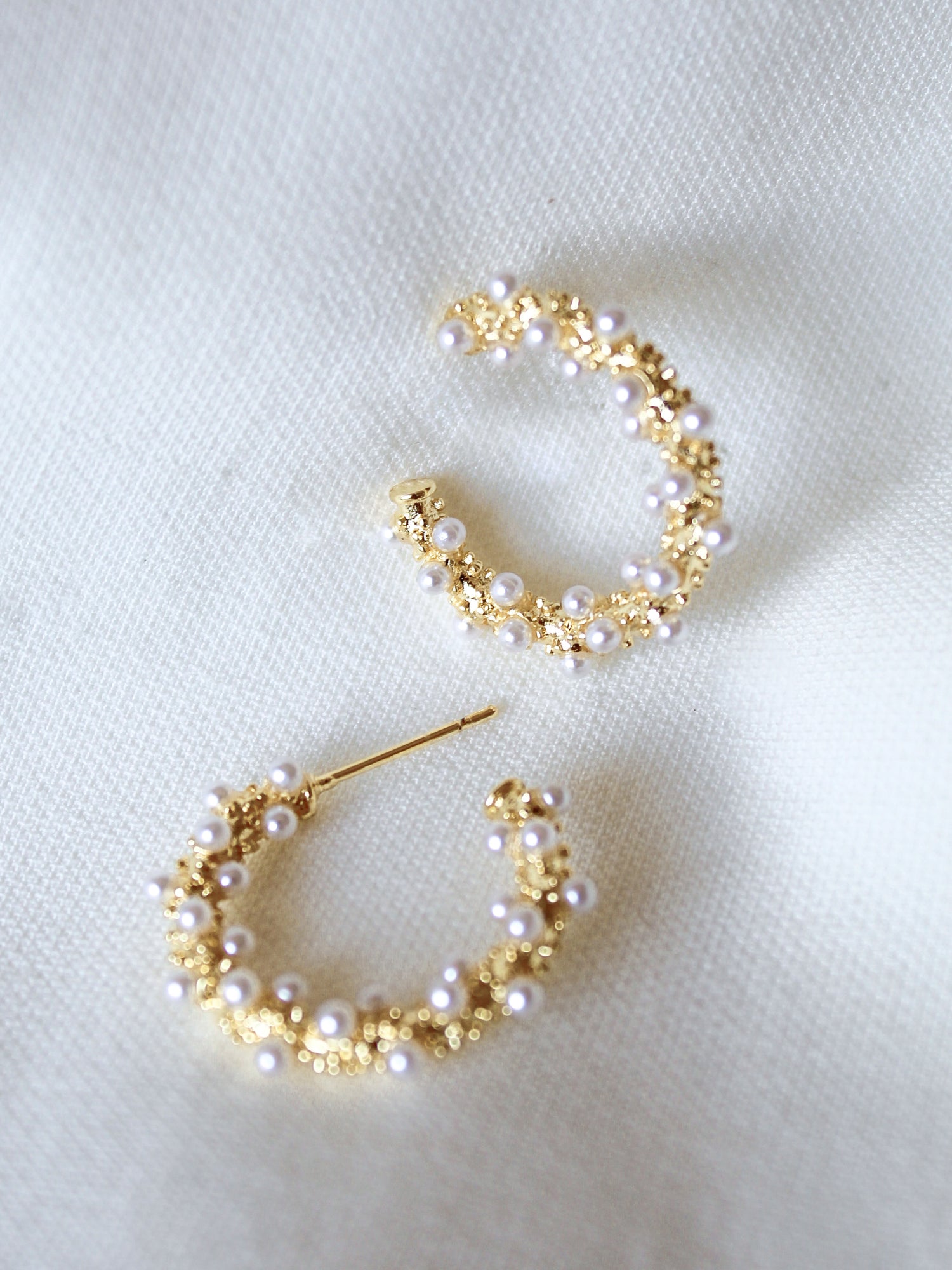 Kinsey Designs Archives' Reef Hoop earrings, 2" gold hoops adorned with small pearls, are displayed on a soft white fabric background; one size fits all.