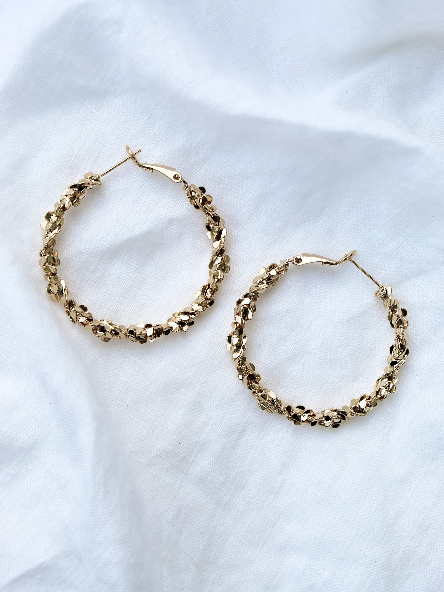The Reese Hoop by Kinsey Designs Archives, featuring gold filled textured hoops with a 1.5" diameter, displayed on soft white fabric.